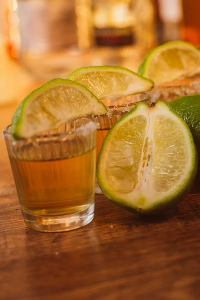 Tequila, limão e sal sobre mesa de madeira — Fotografia de Stock