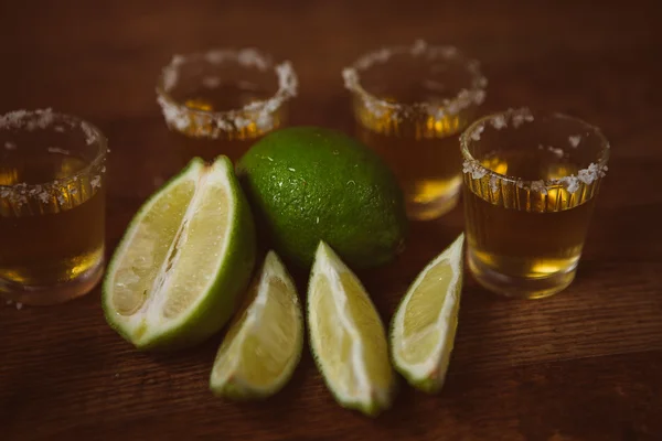 Tequila, vápno a sůl na dřevěný stůl — Stock fotografie