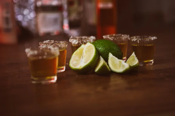 Tequila, limão e sal sobre mesa de madeira — Fotografia de Stock