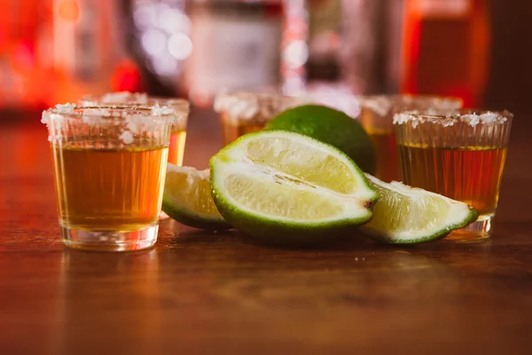 Tequila, lime och salt på träbord — Stockfoto