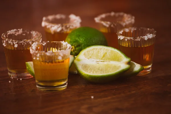 Tequila, limão e sal sobre mesa de madeira — Fotografia de Stock