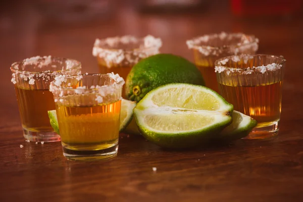 Tequila, limão e sal sobre mesa de madeira — Fotografia de Stock