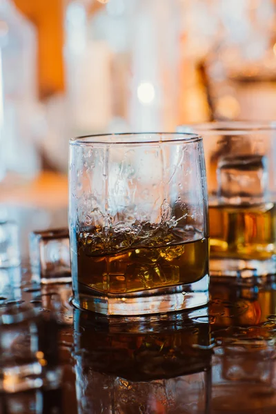 Szkło whisky z lodem i ciepłe światło na czarny stół z odbicia, ciepłą atmosferę — Zdjęcie stockowe