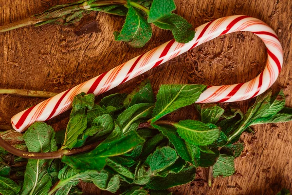 Candy canes with mint leaves  on a wooden background — Stock Photo, Image