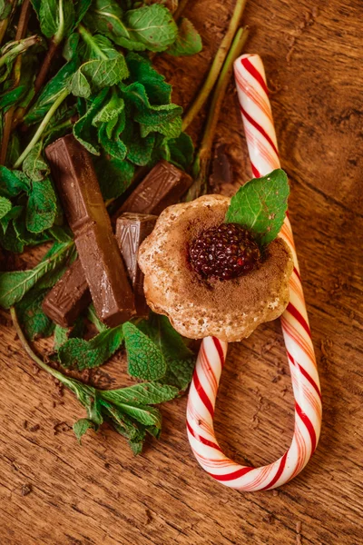 Magdalena de chocolate caramelo de menta con moras y menta en una mesa de madera —  Fotos de Stock