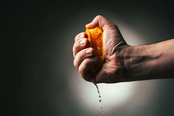 Man dramatic squeezes orange. Conceptis tired from work. — Stock Photo, Image