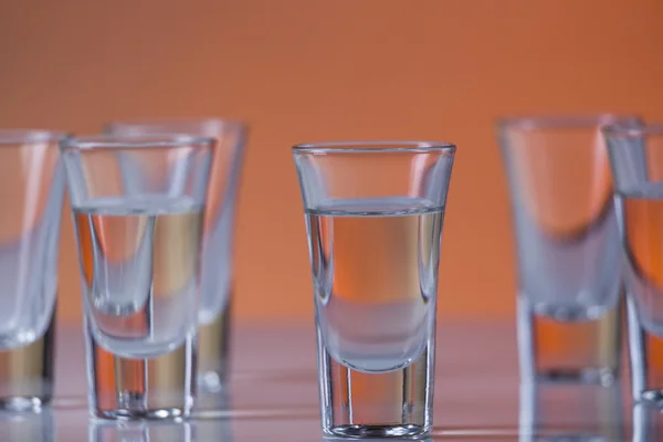 Vidro de tiro cheio de vodka em um fundo laranja — Fotografia de Stock