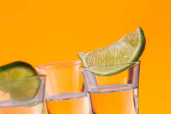用一片柠檬玻璃橙色背景拍摄的龙舌兰酒 — 图库照片