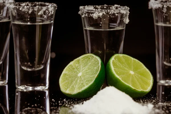 Tequila mit Limette auf schwarzem Hintergrund — Stockfoto