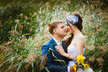 mutlu gelin, yeşil park, ayakta damat öpüşme, gülüyor, gülüyor. düğün günü severler. 