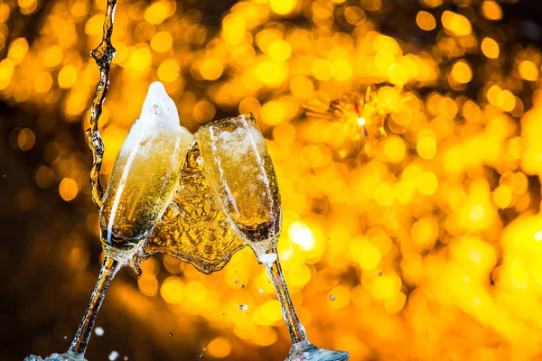 Ein Paar Champagnerflöten mit goldenen Blasen machen Jubel auf goldenem Lichthintergrund mit Platz für Text — Stockfoto