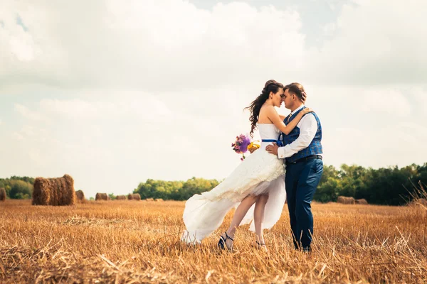 Bride and groom near hay on a rural field — Stock Photo, Image