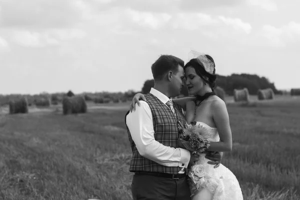 Bride and groom near hay on a rural field — Stock Photo, Image