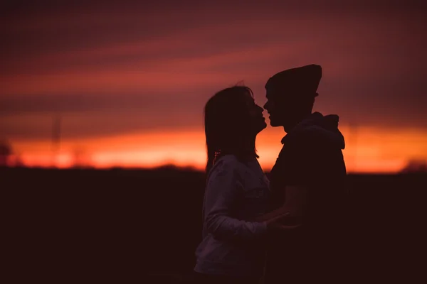 Siluetas de pareja abrazada contra el cielo del atardecer. Foto vintage . —  Fotos de Stock