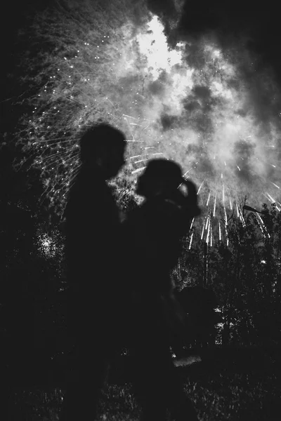 A silhouette of a kissing couple in front of a huge fireworks display. — Stock Photo, Image