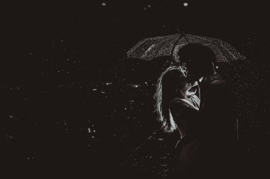 Dramatic photo of a bride and groom in the night rain.