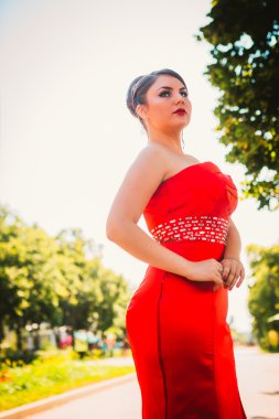 Uzun kırmızı Abiye ayakta ağaçlar ve çalılar arka plan üzerinde güzel kız