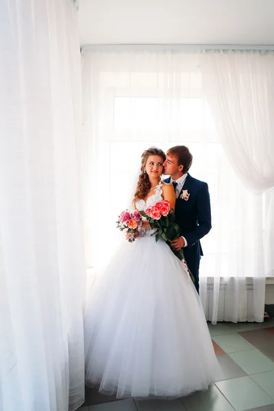 Beautiful young couple posing in the park on a background of windows — Stock Photo, Image