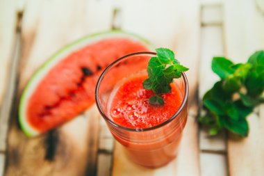 watermelon smoothie and fresh on a light wood background. selective focus to mint