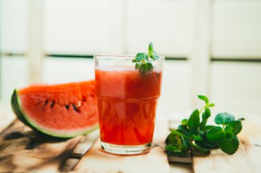 watermelon smoothie and fresh on a light wood background. selective focus to mint