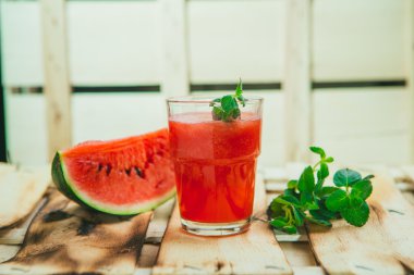 watermelon smoothie and fresh on a light wood background. selective focus to mint