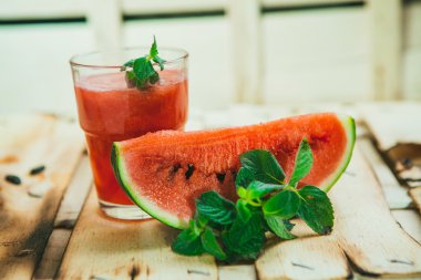 watermelon smoothie and fresh on a light wood background. selective focus to mint