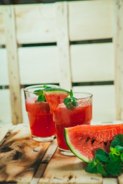 two watermelon smoothie and fresh on a light wood background. selective focus to mint