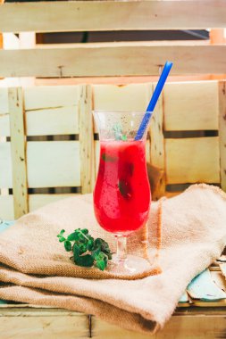 watermelon smoothie and fresh on linen cloth a light wood background with blue straw. selective focus to mint