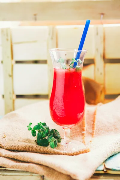 Wassermelonen-Smoothie und frisch auf Leinentuch vor hellem Holzhintergrund mit blauem Stroh. Selektiver Fokus auf Minze — Stockfoto