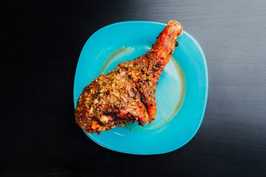 büyük taze pişmiş hindi budu ve siyah ahşap arka plan için mavi tabakta yalan baharatlar serpilir parça dilimlenmiş