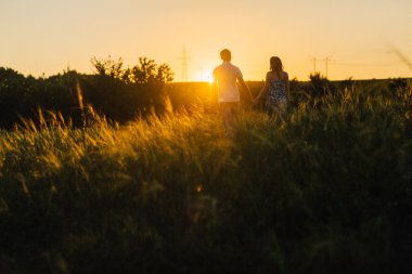 Romantik Çift ayakta ve arka plan yaz çayır sunset bulvarında öpüşme