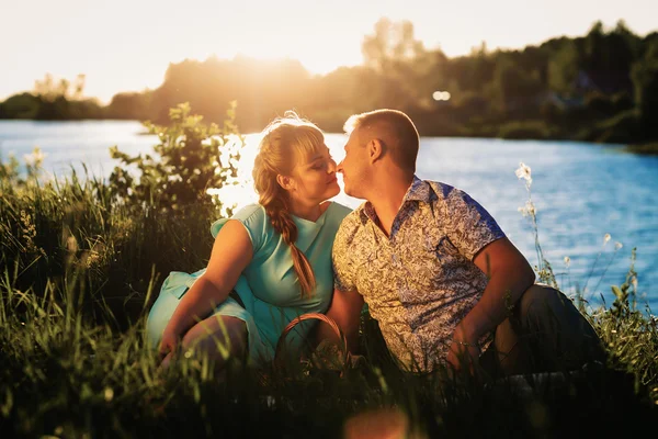 Romantisch paar zitten en zoenen op achtergrond zomer lake — Stockfoto