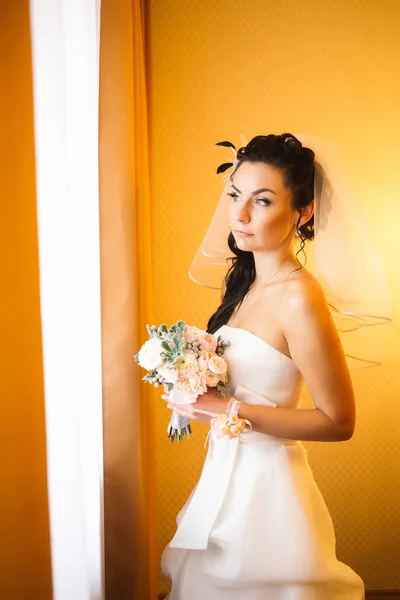 Beautiful young happy  bride standing near the window — Stock Photo, Image