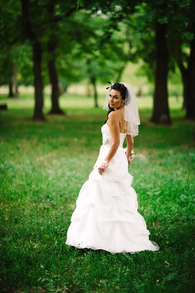 Bella giovane sposa stand su sfondo foresta — Foto Stock