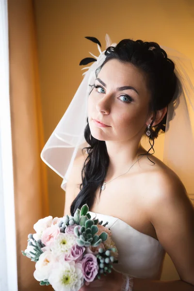 Schöne junge glückliche Braut steht am Fenster — Stockfoto