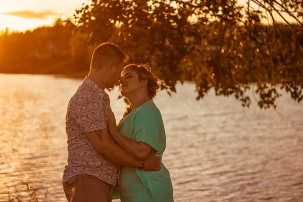 Romantisch paar staande en zoenen op achtergrond zomer meer zonsondergang — Stockfoto