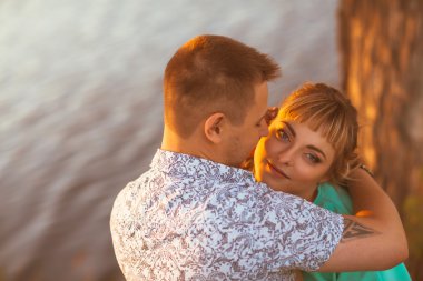 Romantik Çift ayakta ve arka plan yaz göl günbatımı üzerinde öpüşme