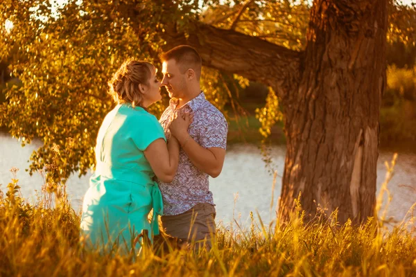 Pareja romántica de pie y besándose en el fondo verano lago puesta del sol — Foto de Stock