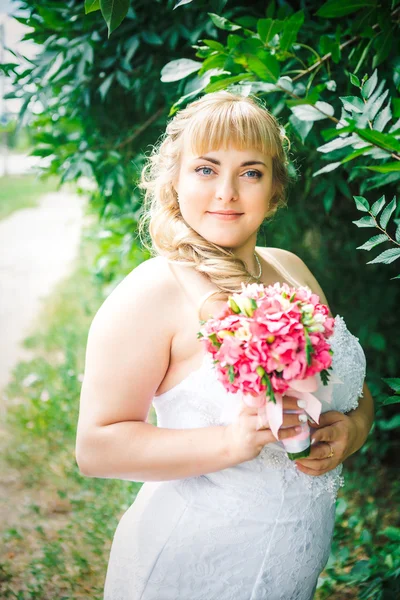 Krásná mladá nevěsta stojí na pozadí lesa — Stock fotografie