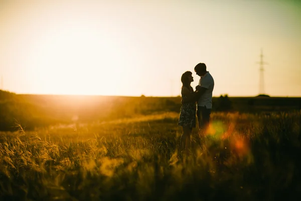 Romantik Çift ayakta ve arka plan yaz çayır sunset bulvarında öpüşme — Stok fotoğraf