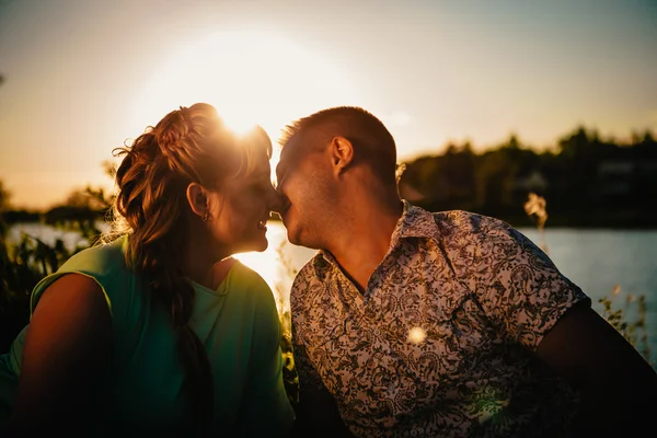 Romantisches Paar sitzt und küsst sich im Hintergrund Sommersee — Stockfoto