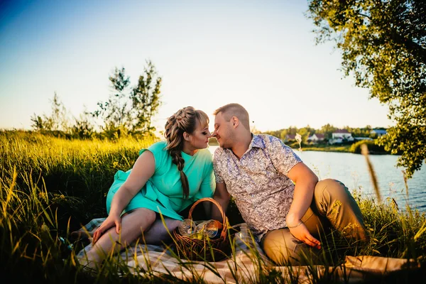 Romantisch paar zitten en zoenen op achtergrond zomer lake — Stockfoto