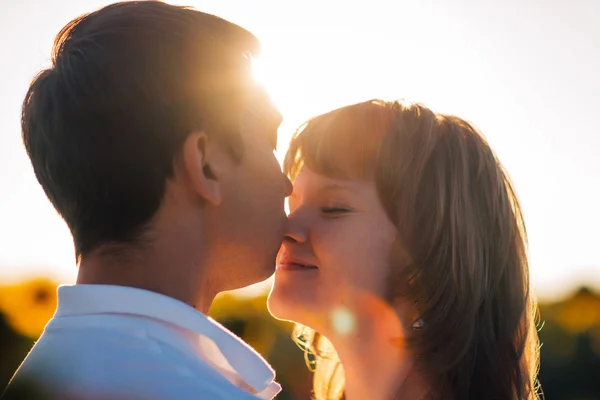 Coppia romantica in piedi e baciare sullo sfondo campo estivo tramonto girasole — Foto Stock
