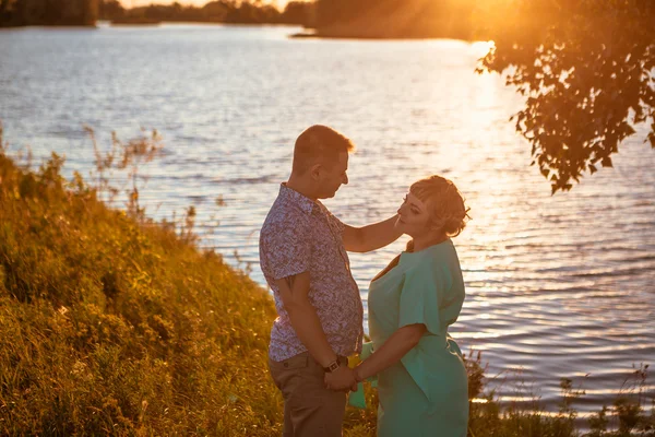Pareja romántica de pie y besándose en el fondo verano lago puesta del sol —  Fotos de Stock