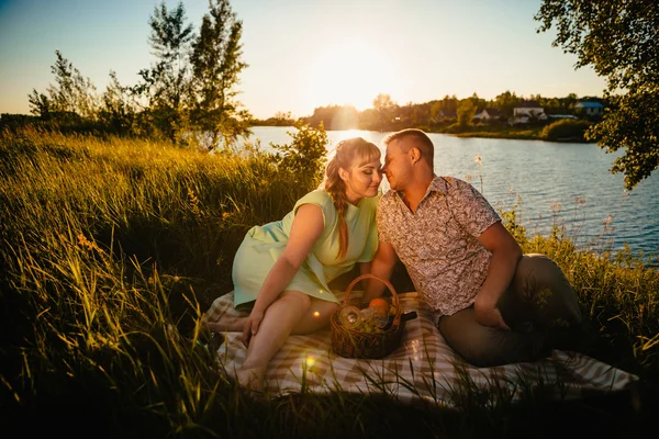 Romantisches Paar sitzt und küsst sich im Hintergrund Sommersee — Stockfoto