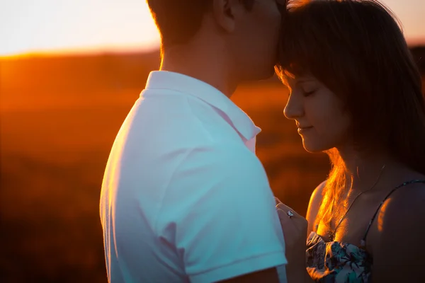 Pareja romántica de pie y besándose en el fondo verano pradera puesta de sol — Foto de Stock