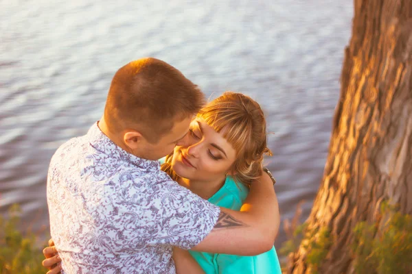 Romantik Çift ayakta ve arka plan yaz göl günbatımı üzerinde öpüşme — Stok fotoğraf