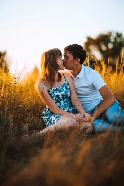 Pareja romántica de pie y besándose en el fondo verano pradera puesta de sol —  Fotos de Stock