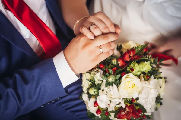 Hands of bride and groom on the bouquet — Stock Photo, Image