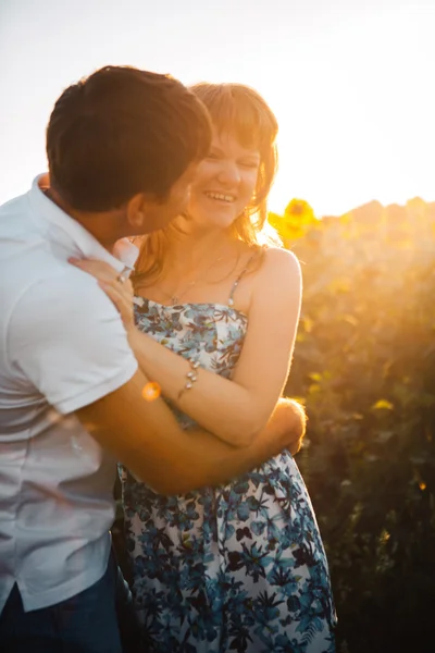 Pareja romántica de pie y besándose en el fondo campo de verano girasol puesta de sol —  Fotos de Stock